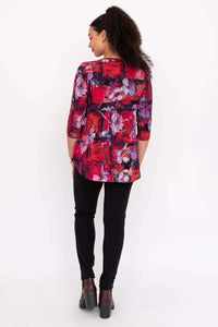 Back view of model wearing a floral red and purple print top, black pants, and brown boots