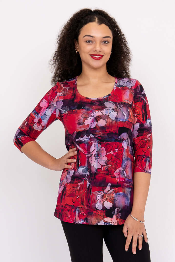 Front view of model wearing a vibrant red and purple floral 3/4 sleeve top