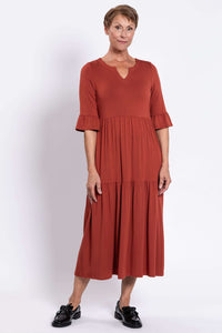Model posing in rust-colored tiered midi dress with 3/4 ruffled sleeves
