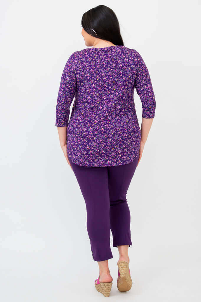 Back view of woman in a violet floral 3/4 sleeve top and purple pants