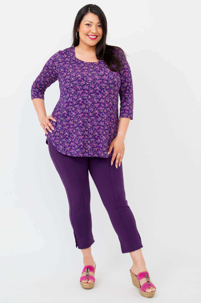 Full body front view of woman wearing purple floral 3/4 sleeve top and purple pants