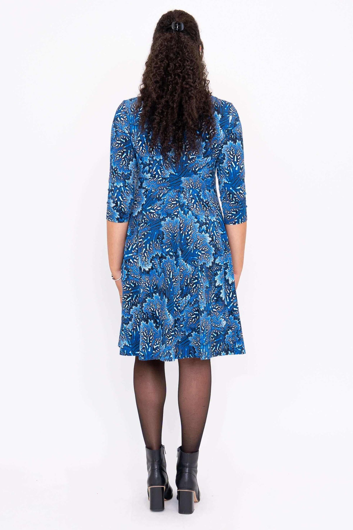 Back view of a blue bamboo dress with 3/4 sleeves and a floral pattern on a woman