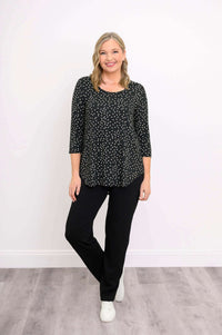 Woman in black polka dot 3/4 sleeve shirt, black pants, and white sneakers