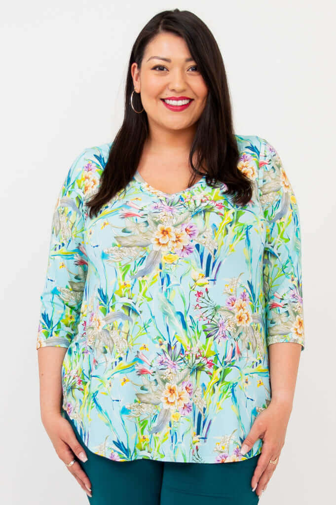 Woman wearing a light blue floral V-neck top with 3/4 sleeves, smiling