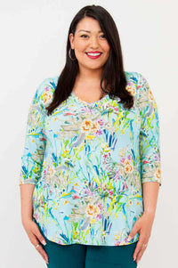 Woman wearing a light blue floral V-neck top with 3/4 sleeves, smiling