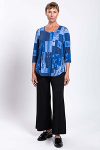 Model posing in blue patchwork Jazz 3/4 sleeve top and black wide-leg pants