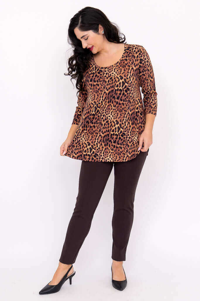 Woman looking down in a flowy leopard print 3/4 sleeve top and dark trousers