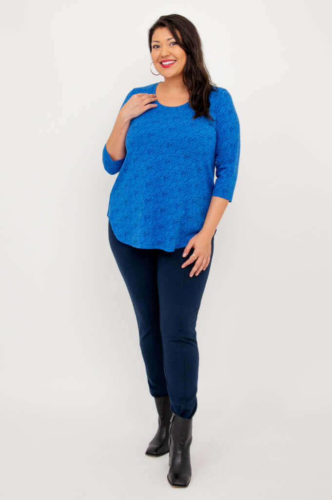 Woman posing in sapphire blue 3/4 sleeve top and navy pants, angled front view