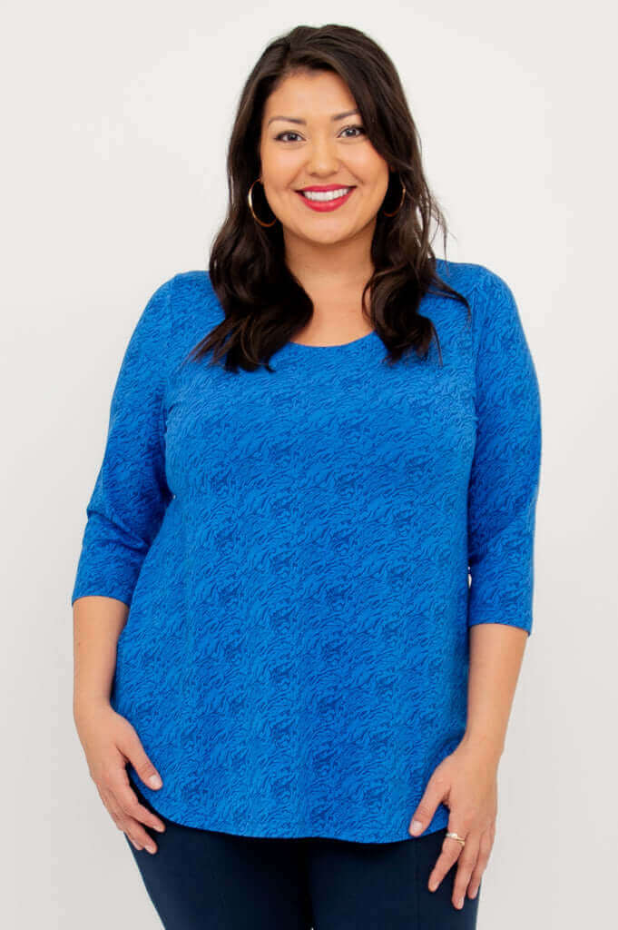 Woman wearing a sapphire blue textured 3/4 sleeve top, smiling, front view