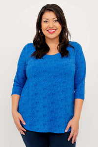 Woman wearing a sapphire blue textured 3/4 sleeve top, smiling, front view