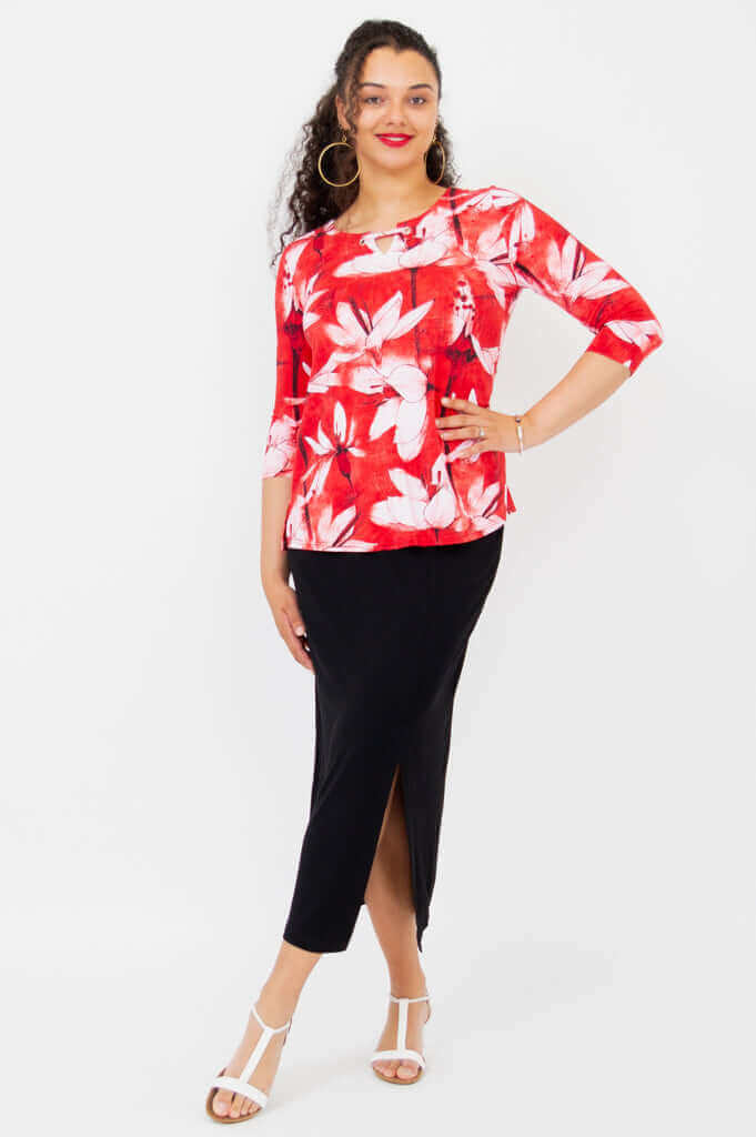 Front view of a woman in a red and white floral top with black skirt and white sandals