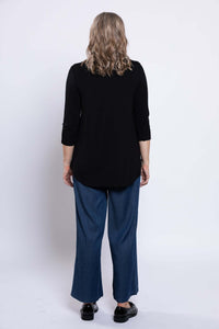 Woman wearing a black 3/4 sleeve top and blue jeans, back view