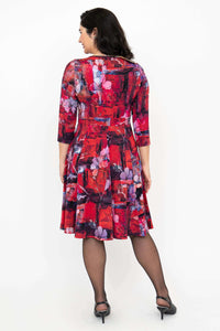 Back view of a woman wearing a red and purple floral dress with fit and flare silhouette and 3/4 sleeves