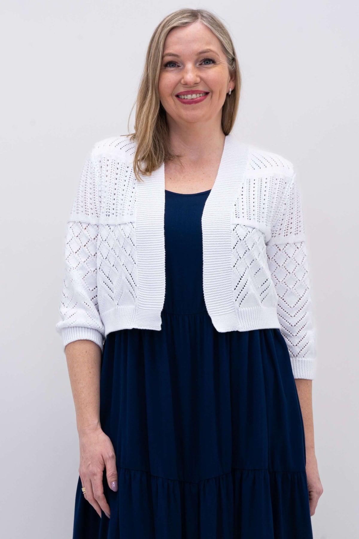Front view of woman wearing a white cropped knit sweater with 3/4 sleeves