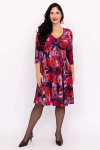 Front view of a woman wearing a vibrant red floral fit and flare dress with V-neckline and 3/4 sleeves