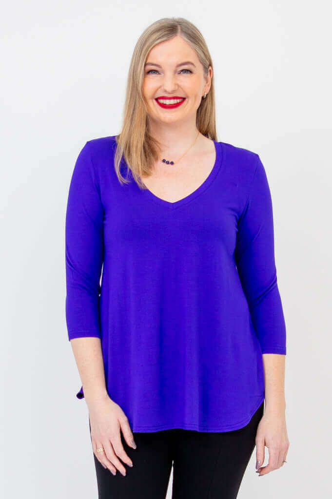 Woman wearing a sapphire blue V-neck bamboo top with 3/4 sleeves, smiling at the camera