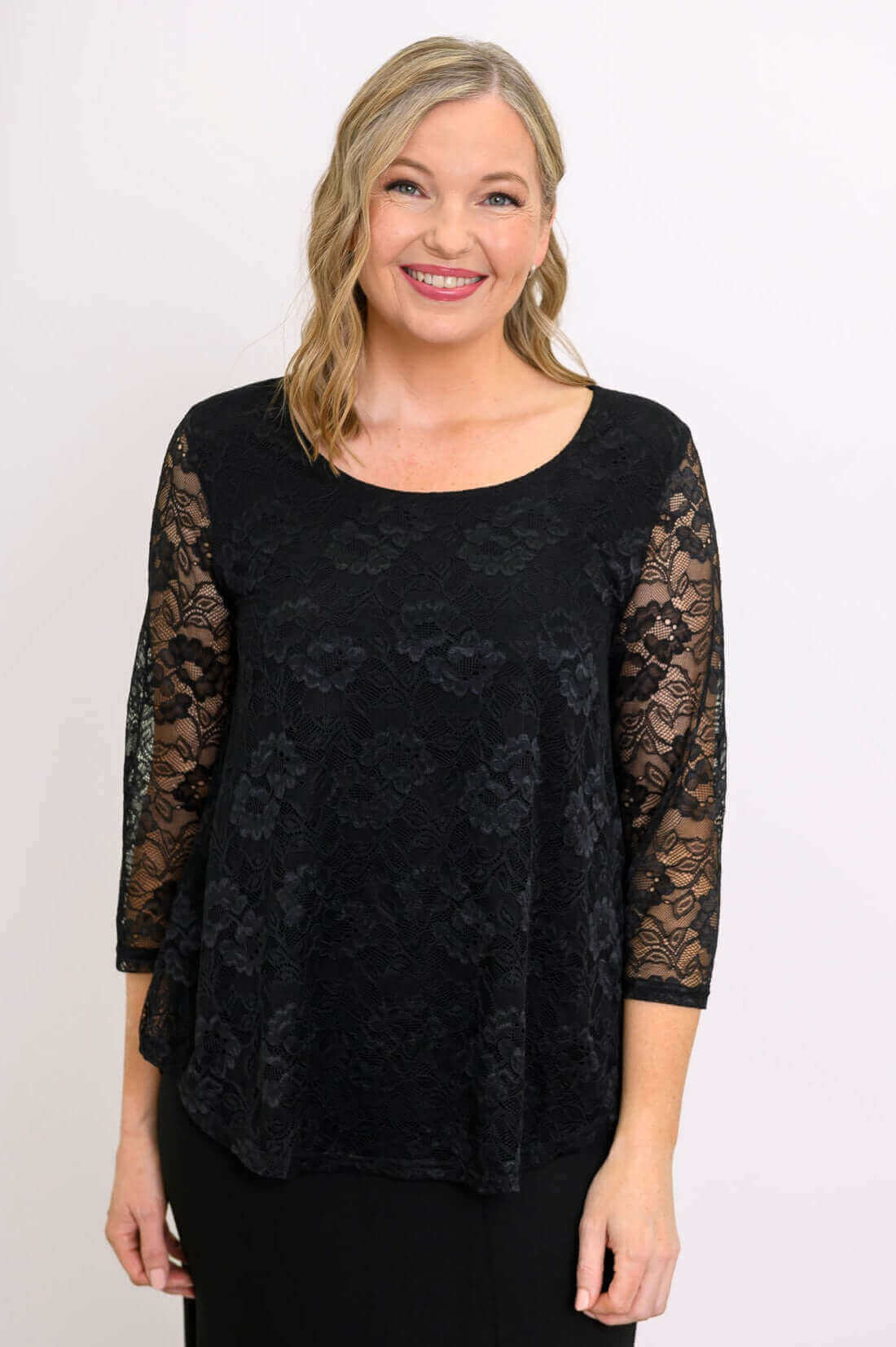 Woman wearing a black lace overlay top with scoop neckline and 3/4 sleeves