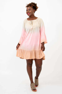 Smiling woman in an ombre dress with ruffle details and tassel tie