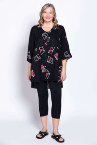 Front-facing look at a woman in a patterned high-low hem blouse with 3/4 bell sleeves