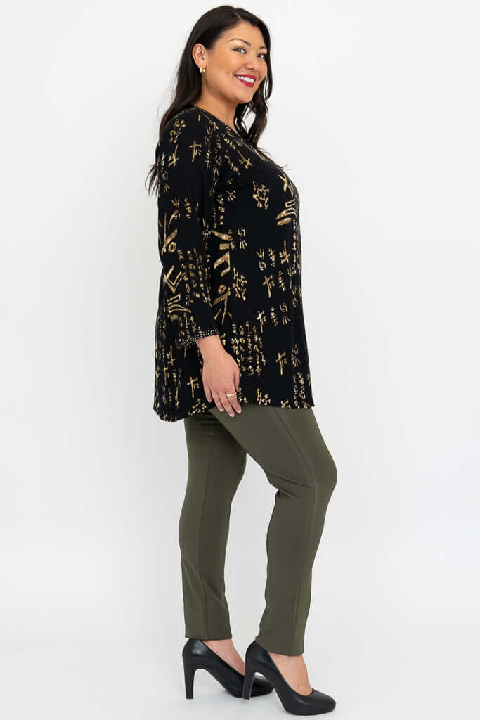 Side profile of woman in black batik blouse with 3/4 sleeves and olive pants