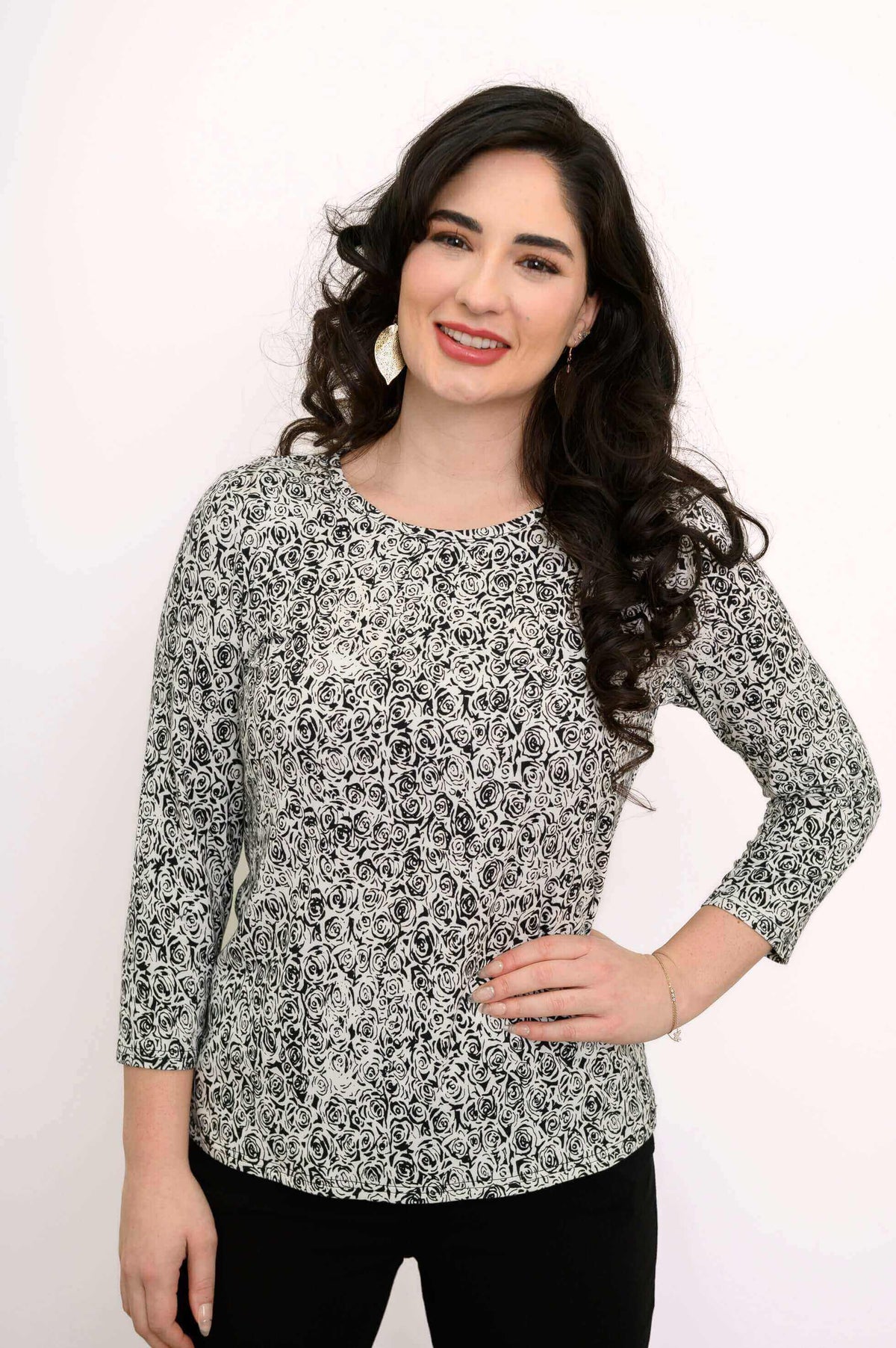 Woman smiling in a fitted black and white rose print tee with 3/4 sleeves