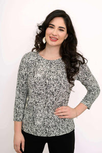 Woman smiling in a fitted black and white rose print tee with 3/4 sleeves