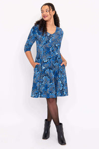 Woman modeling blue V-neck dress with side pockets, 3/4 sleeves, and floral print