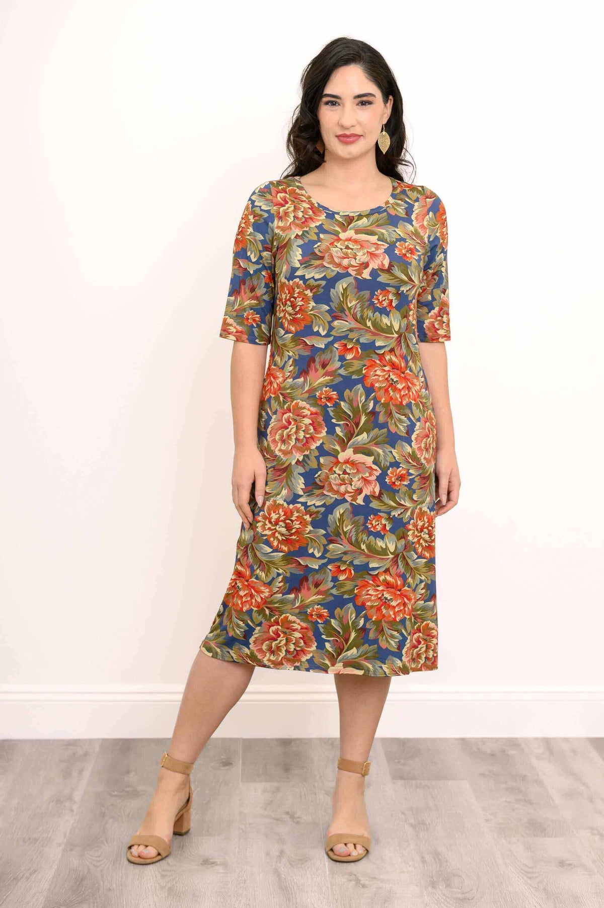 Woman modeling a blue and orange floral dress with 3/4 sleeves, standing straight