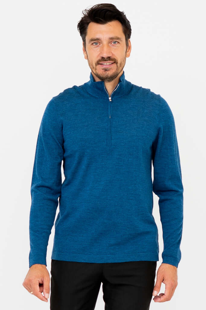 Front view of man in a blue 1/4 zip sweater with mock turtleneck and black pants