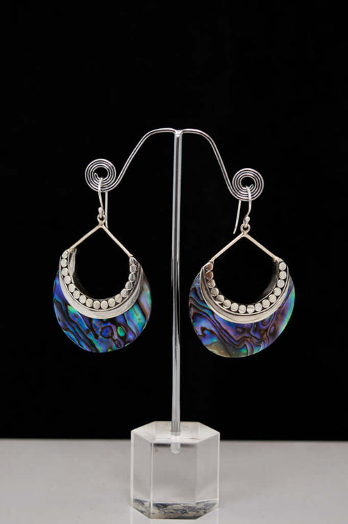 Pair of abalone and sterling silver crescent earrings displayed on a stand