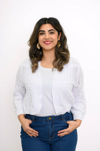 Woman wearing a white knit cardigan on a white top and blue jeans against a white background