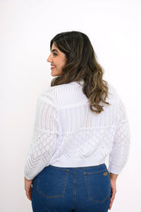 Close-up back view of woman wearing pointelle knit cropped cardigan and denim pants