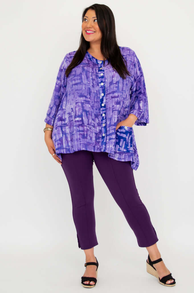 Angled view of model wearing a purple tunic with front buttons and pockets