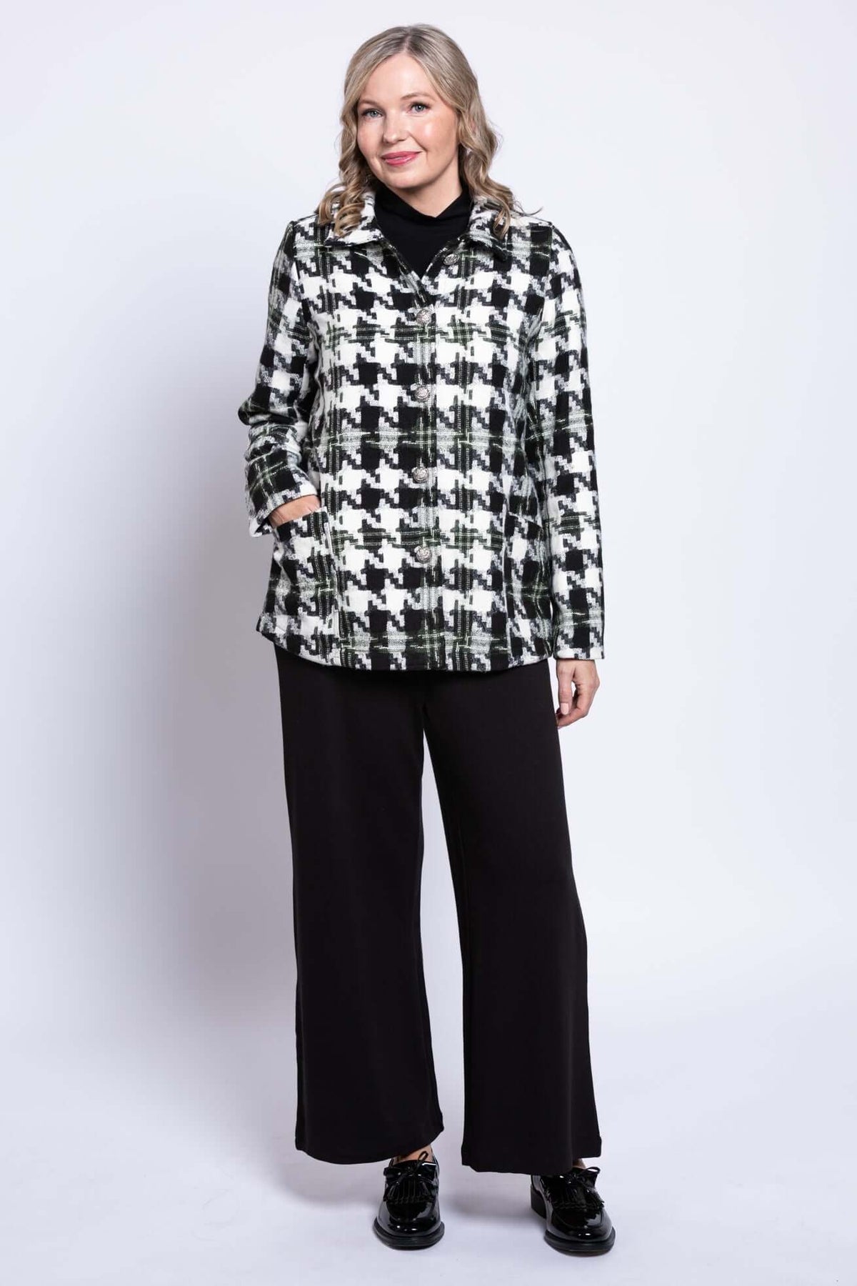 Slight angled front view of woman modeling a black and white houndstooth coat