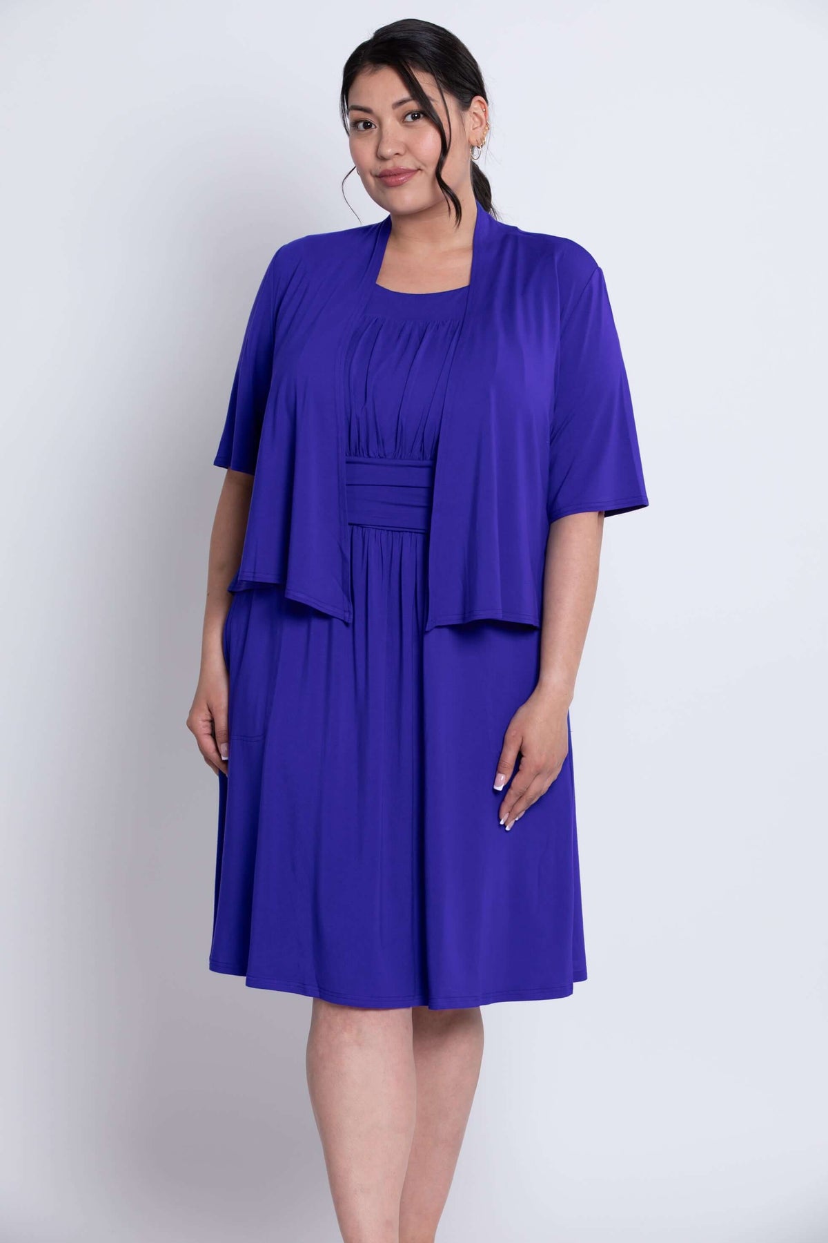 Three-quarter front angled view of model in cobalt blue cropped jacket and matching dress