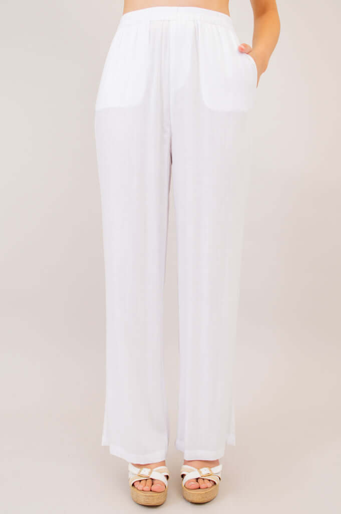 Angled front view of white wide leg pants with hand in pocket