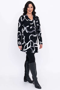 Angled view of tunic with bold abstract print, worn over leggings and boots.