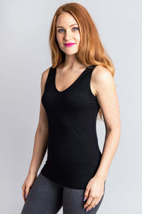 Woman in a black V-neck bamboo tank top, angled pose with grey leggings