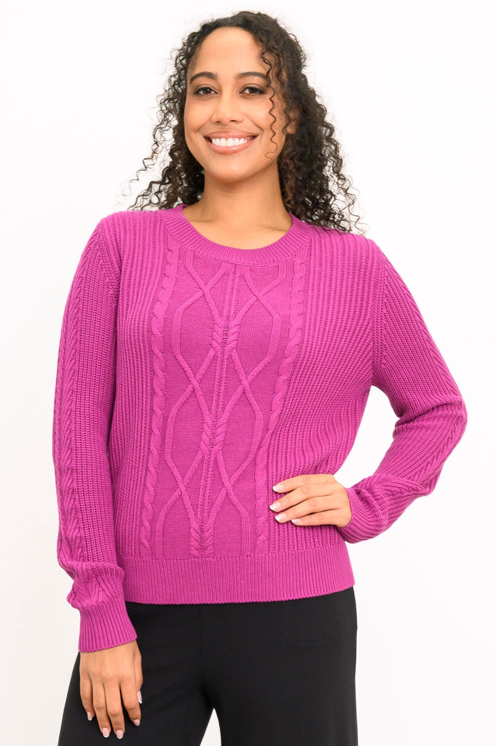 Front view of female model wearing a long-sleeve sweater in a vibrant rose-pink hue with a round neck, hand on hip, against a white backdrop.