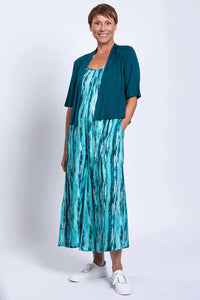 Woman in aqua blue jumpsuit styled with a teal open cardigan