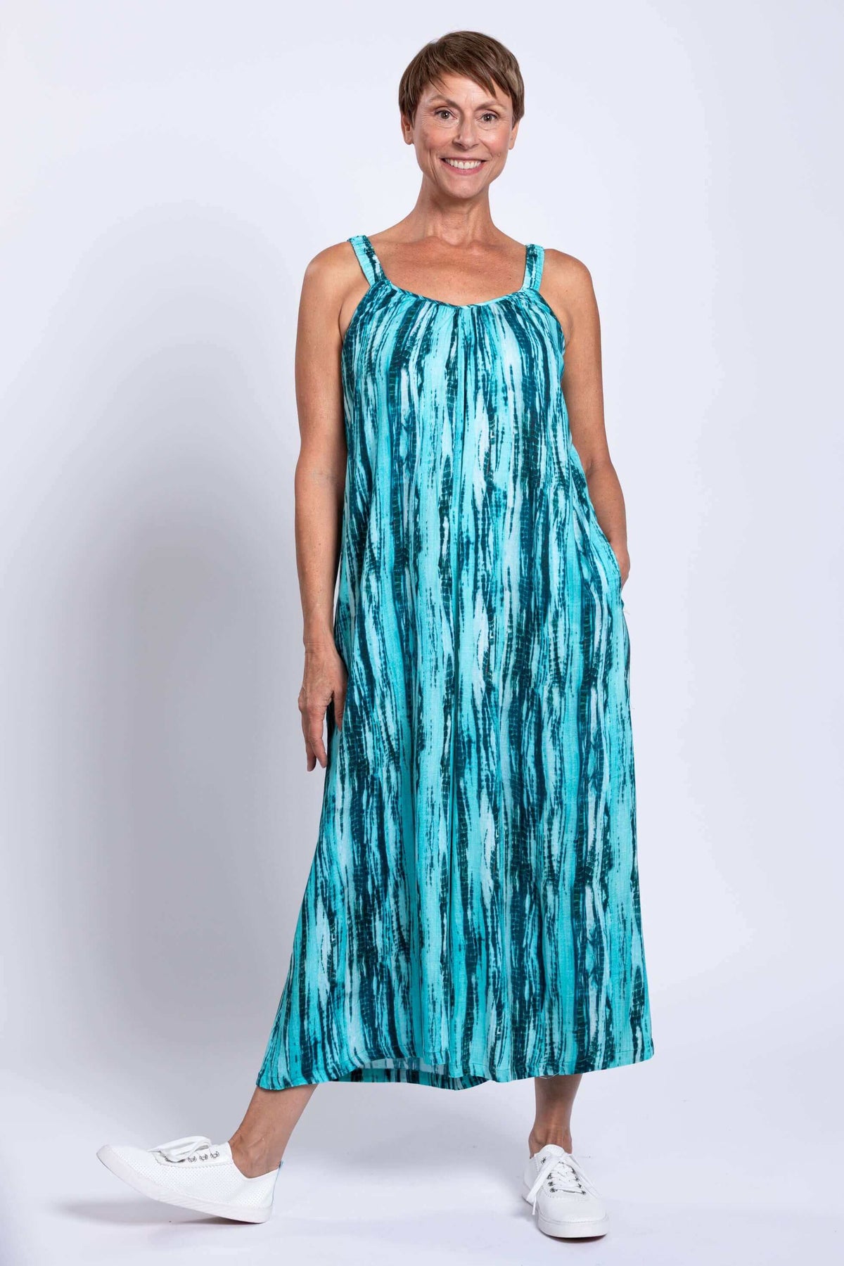 Woman smiling in aqua blue sleeveless jumpsuit with pockets