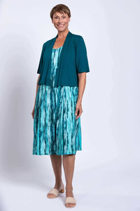 Woman in aqua streak sleeveless dress paired with teal shrug, standing confidently