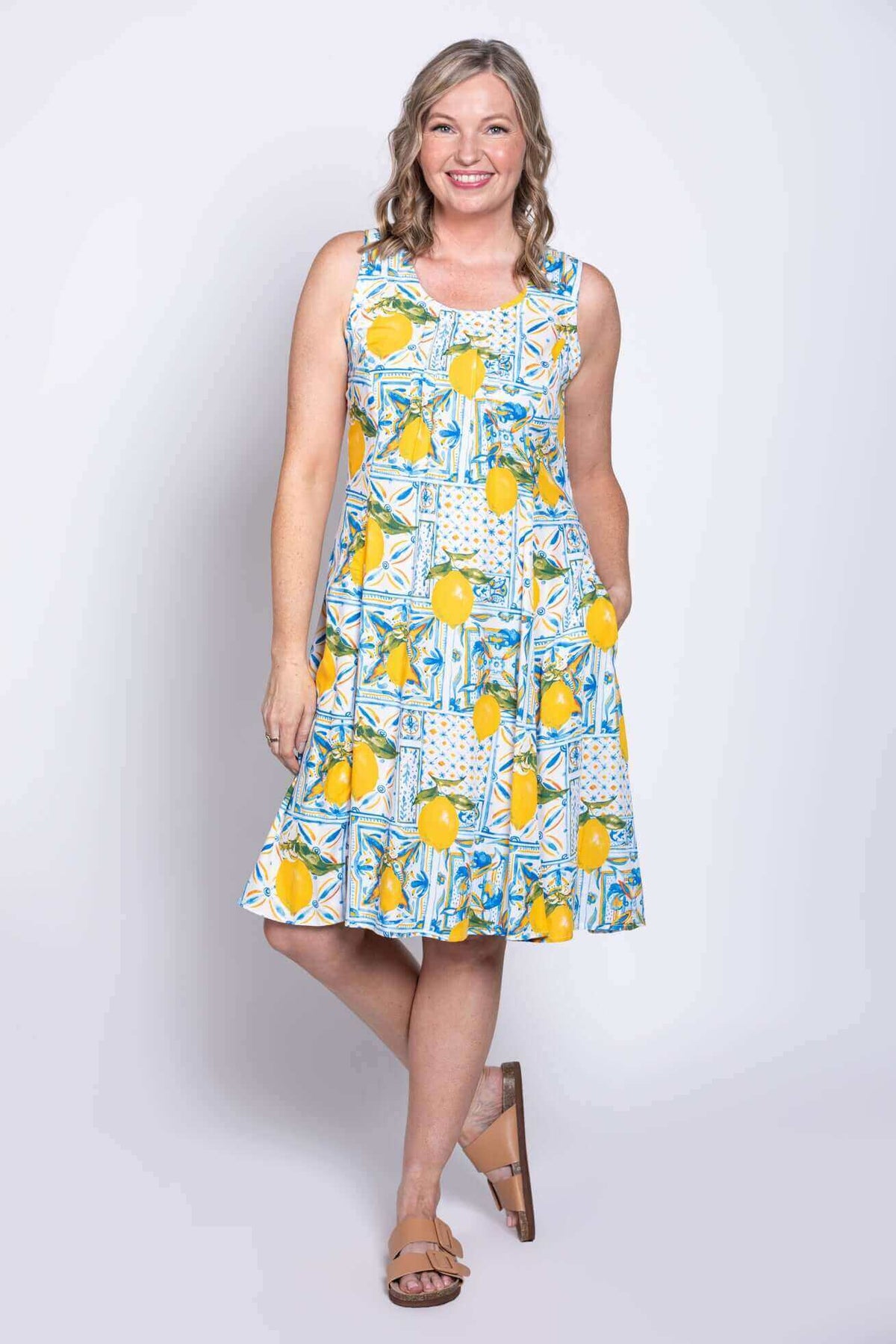 Model smiling in a sleeveless lemon print dress with A-line silhouette and pockets