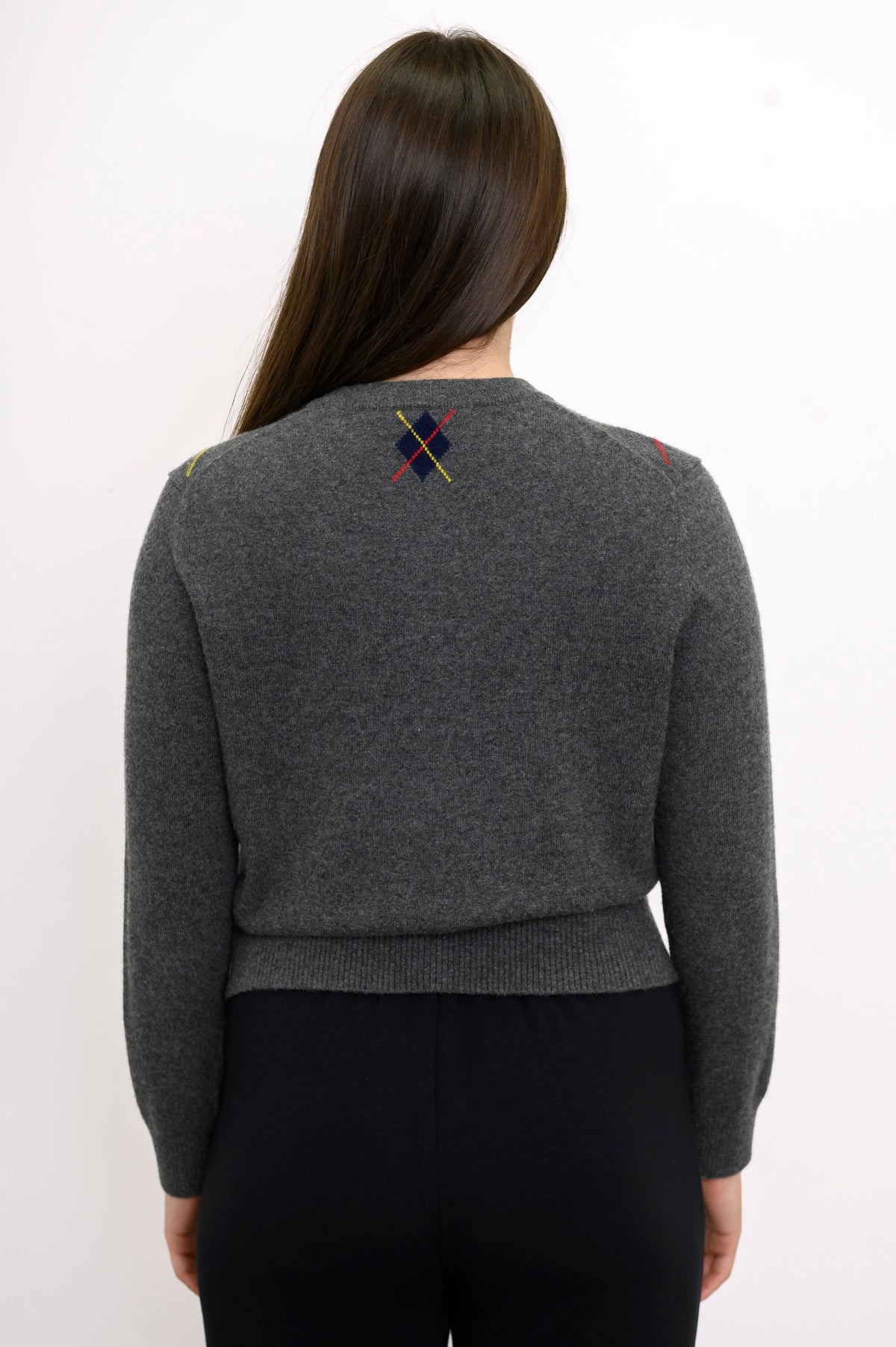Close up back view of woman wearing grey knit sweater with ribbed hem and relaxed fit