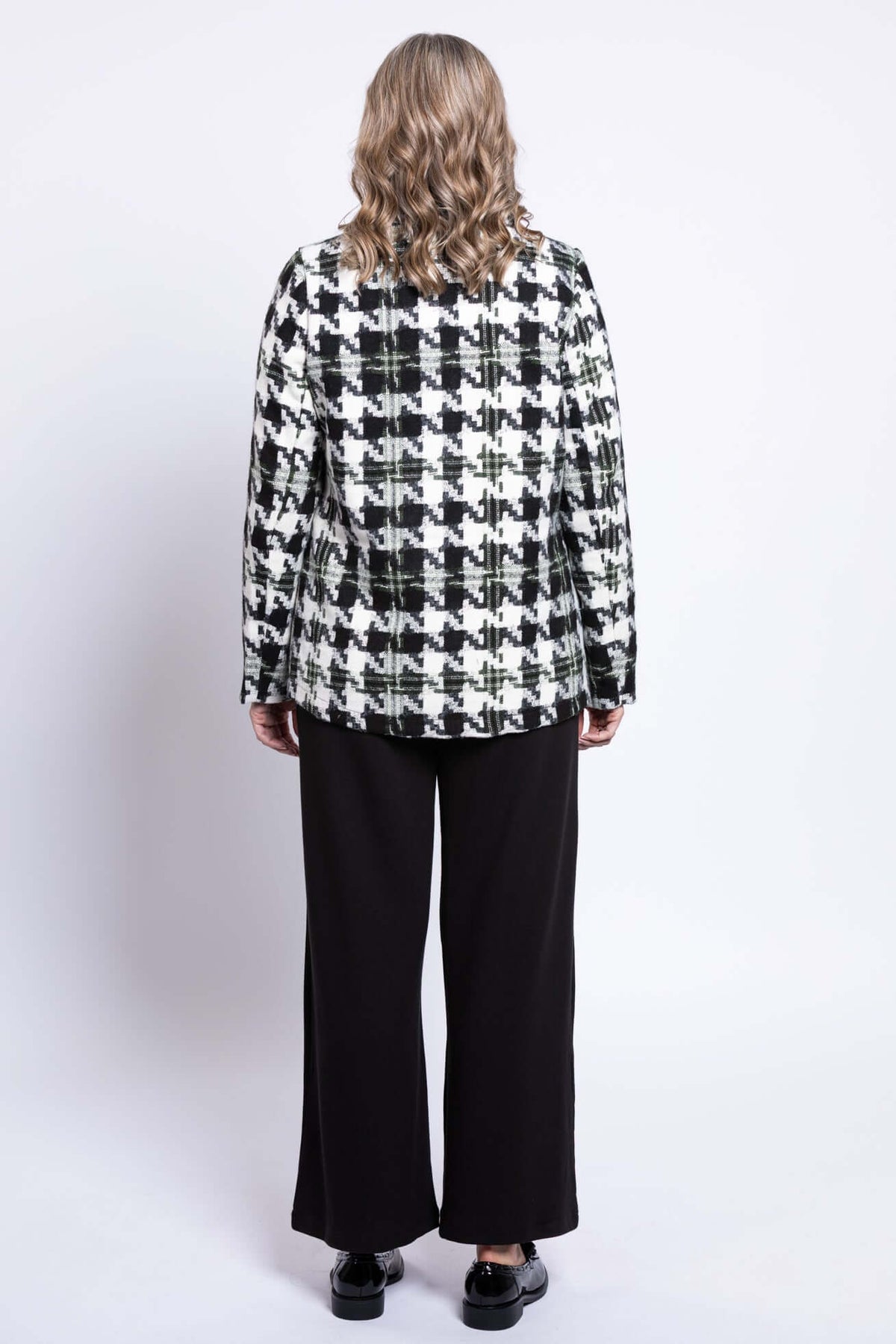 Back view of woman wearing a black and white houndstooth pattern coat