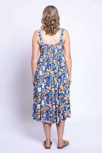 Back view of a woman wearing a sleeveless citrus floral dress with shirred bodice