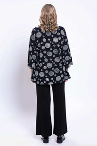 Back view of model showing black blouse with white circular print