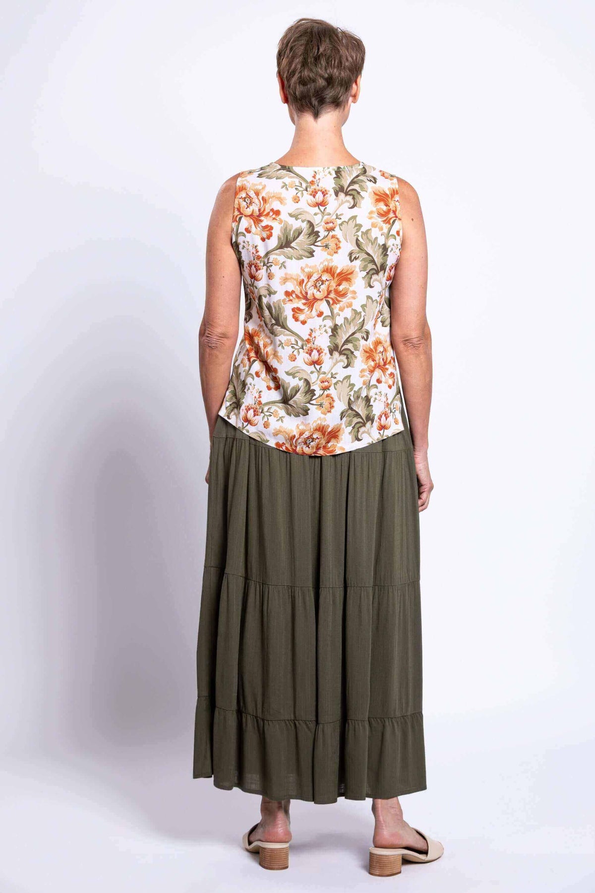Back view of woman wearing the floral sleeveless V-neck tank top and olive green skirt
