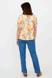 Back view of woman in a bird motif short sleeve tee and blue pants