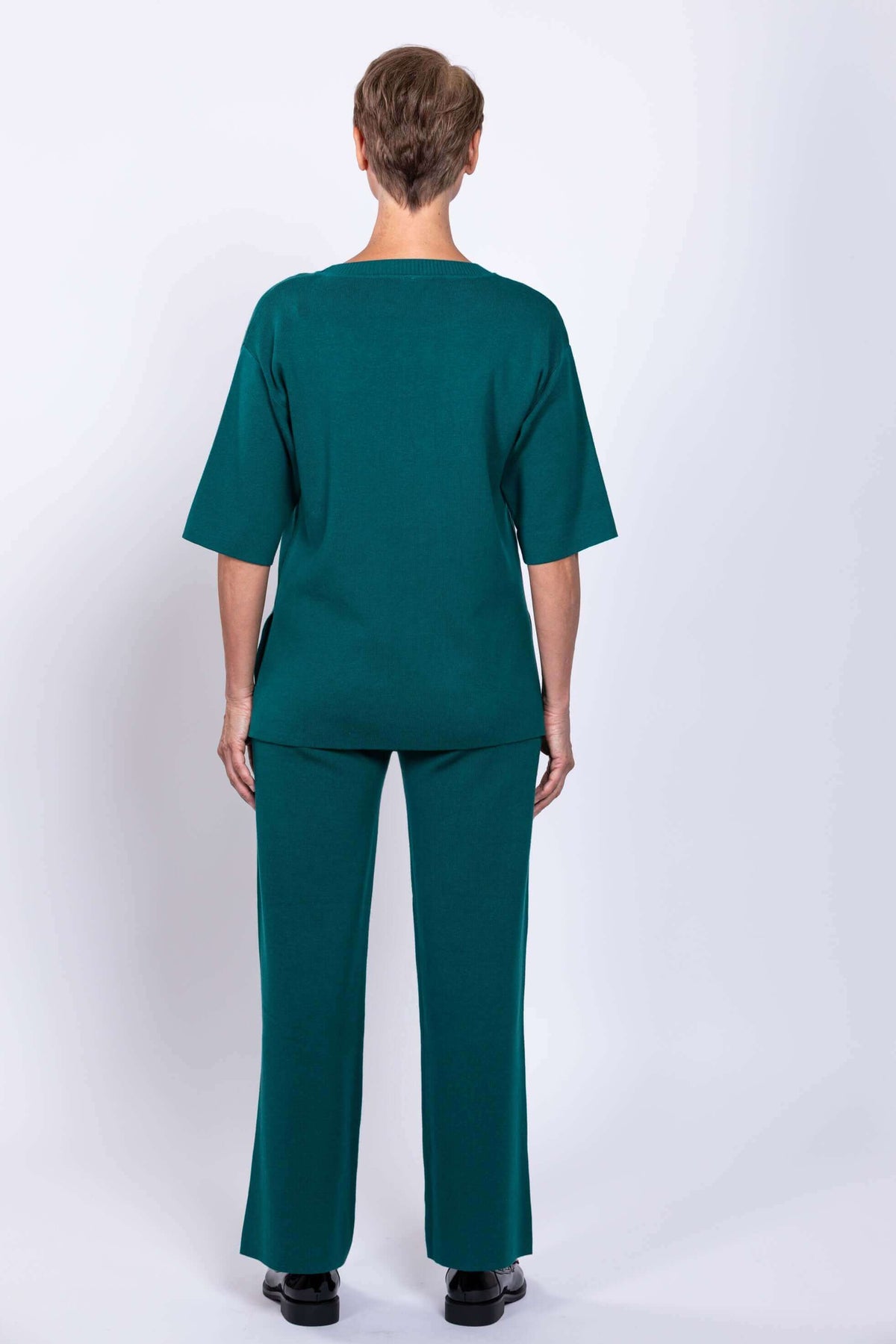 Rear profile shot of a long sleeve teal viscose cotton top displaying a relaxed back seam construction.